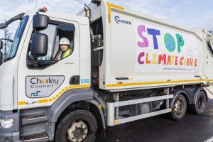 Olivia, 10, stands in front of her Climate Change poster on a Chorley Council bin truck